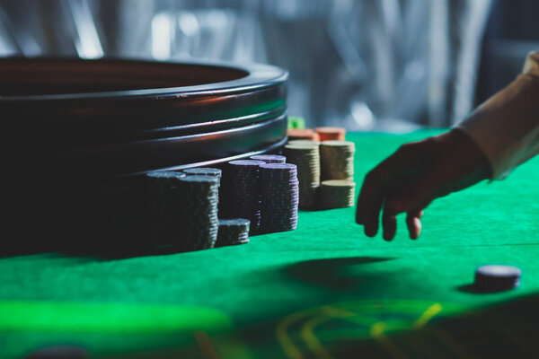 Крупный план яркого изображения разноцветного стола казино с рулеткой в движении, с рукой крупье, и группа азартных игр богатых богатых людей
 