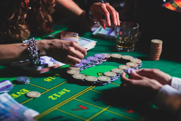 Uma imagem vibrante de close-up de mesa de cassino multicolorido com roleta em movimento, com a mão de croupier, e um grupo de pessoas ricas em jogos de azar — Fotografia de Stock