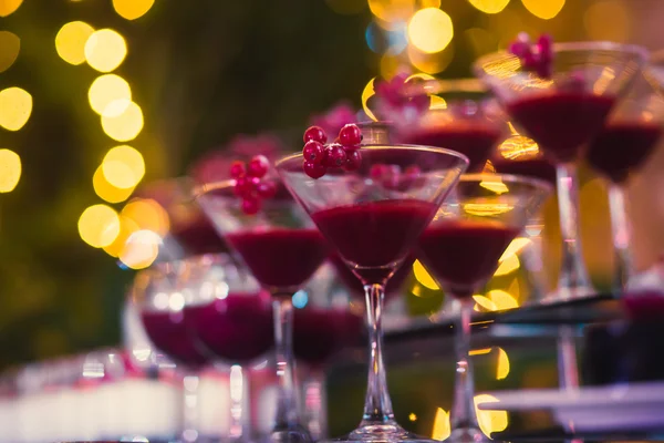 Beautiful row line of different colored alcohol cocktails with mint on a open air party, martini, vodka with bubbles,and others on decorated catering bouquet wedding table on open air event, in nigh — Stock Photo, Image