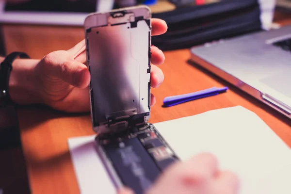 En närbild processen att demontera och avveckla modern mobiltelefon smartphone med brutna krossade display glas och ändra Detaljer hemma — Stockfoto