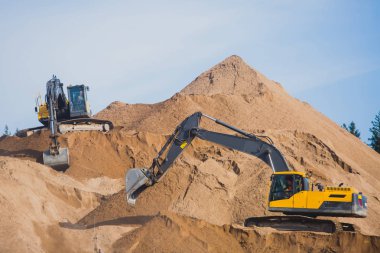 Sarı ağır ekskavatör ve kum kazı ve yol çalışmaları, boşaltma kum ve yol metal sırasında yeni bir yol inşaatı sırasında çalışma buldozer