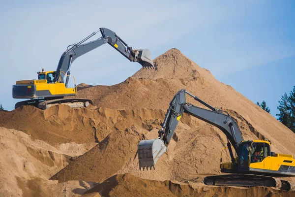 Escavadora pesada amarela e escavadora escavando areia e trabalhando durante obras rodoviárias, descarregando areia e metal rodoviário durante a construção da nova estrada — Fotografia de Stock