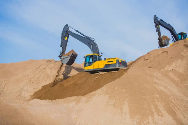 Escavadora pesada amarela e escavadora escavando areia e trabalhando durante obras rodoviárias, descarregando areia e metal rodoviário durante a construção da nova estrada — Fotografia de Stock