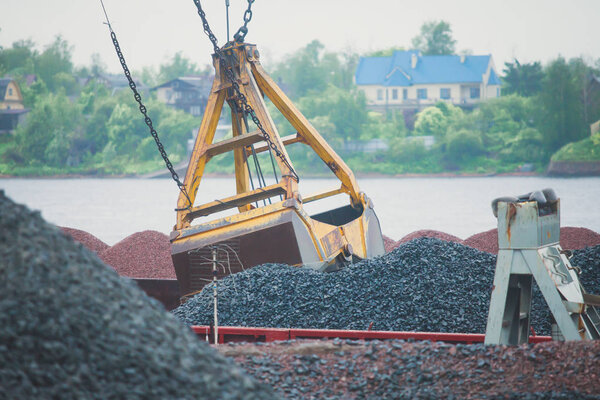 Yellow heavy excavator and bulldozer excavating sand and working during road works, unloading sand and road metal during construction of the new road