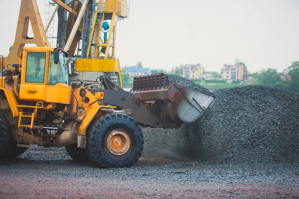 Escavadora pesada amarela e escavadora escavando areia e trabalhando durante obras rodoviárias, descarregando areia e metal rodoviário durante a construção da nova estrada — Fotografia de Stock