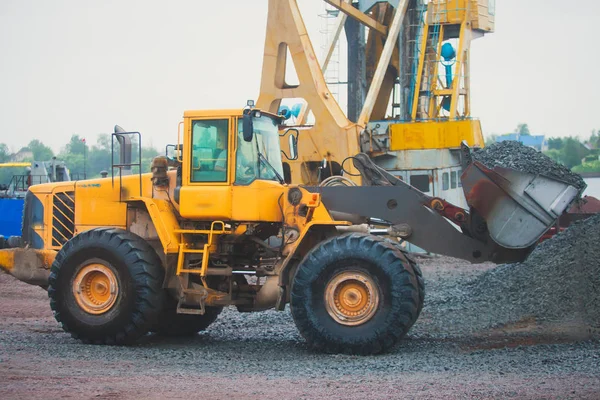 Yellow heavy excavator and bulldozer excavating sand and working during road works, unloading sand and road metal during construction of the new road — Stock Photo, Image