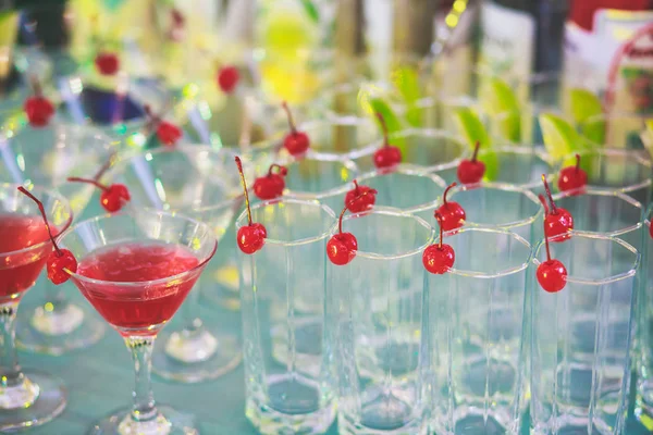 Beautiful row line of different colored alcohol cocktails on a party, martini, vodka,and others on decorated catering bouquet table on open air event, picture with beautiful bokeh — Stock Photo, Image