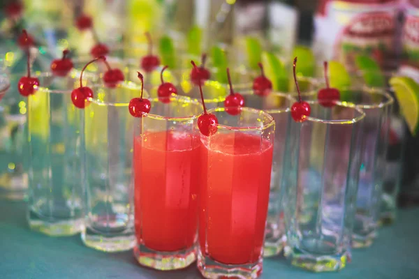 Hermosa línea de fila de cócteles de alcohol de diferentes colores en una fiesta, martini, vodka y otros en la mesa de ramo de catering decorado en el evento al aire libre, imagen con hermoso bokeh — Foto de Stock