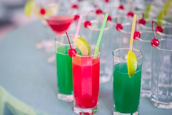 Vackra raden av olika färgade alkohol drinkar på en fest, martini, vodka och andra på inredda med självhushåll bukett bord på utomhus händelse, bild med vacker bokeh — Stockfoto