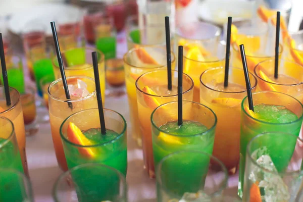 Linha de linha bonita de diferentes coquetéis de álcool coloridos em uma festa, martini, vodka e outros na mesa de buquê de catering decorada em evento ao ar livre, imagem com belo bokeh — Fotografia de Stock