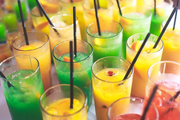 Linha de linha bonita de diferentes coquetéis de álcool coloridos em uma festa, martini, vodka e outros na mesa de buquê de catering decorada em evento ao ar livre, imagem com belo bokeh — Fotografia de Stock