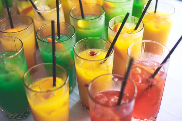 Hermosa línea de fila de cócteles de alcohol de diferentes colores en una fiesta, martini, vodka y otros en la mesa de ramo de catering decorado en el evento al aire libre, imagen con hermoso bokeh —  Fotos de Stock