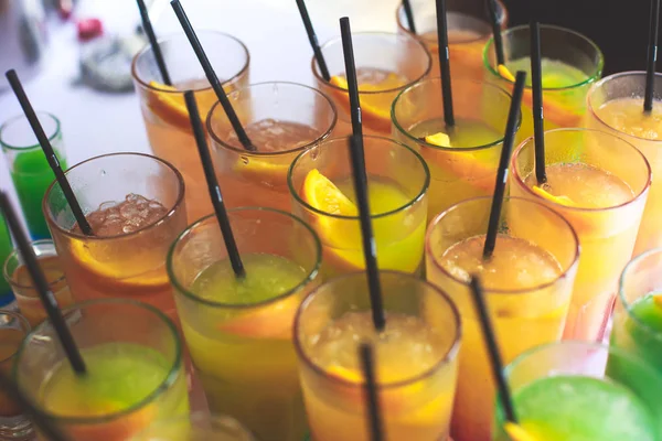 Beautiful row line of different colored alcohol cocktails on a party, martini, vodka,and others on decorated catering bouquet table on open air event, picture with beautiful bokeh — Stock Photo, Image