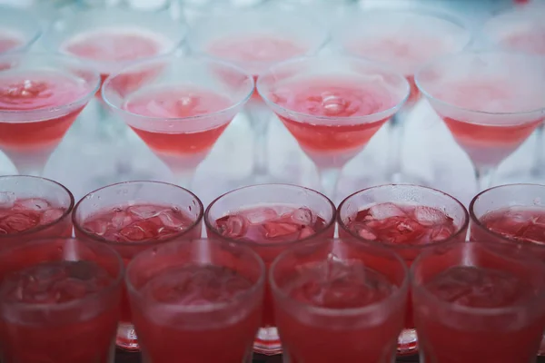 Hermosa línea de fila de cócteles de alcohol de diferentes colores en una fiesta, martini, vodka y otros en la mesa de ramo de catering decorado en el evento al aire libre, imagen con hermoso bokeh — Foto de Stock