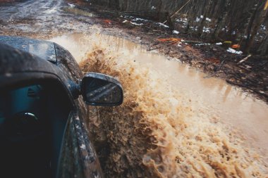 Bir jeeping yarışma sırasında çamurlu su birikintisi, büyük bir sıçrama ile off-road iz yolu ile SUV 4wd araba sürmek