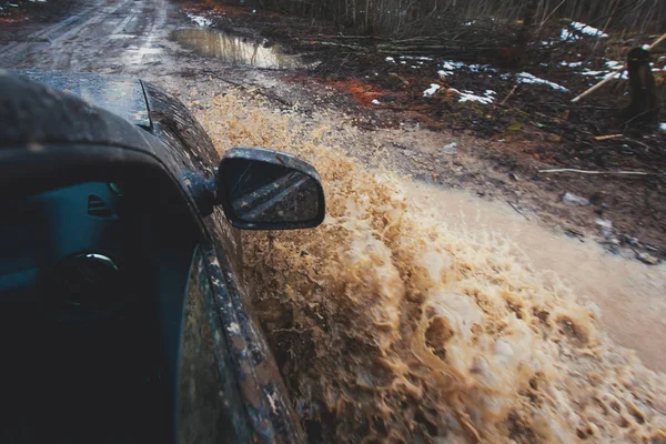 Suv 4wd coche paseos a través de charco fangoso, camino de la pista fuera de la carretera, con un gran chapoteo, durante una competencia jeeping —  Fotos de Stock