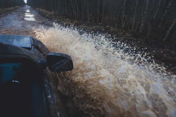 Сув 4wd автомобіль їде через брудну калюжу, бездоріжжя, з великим сплеском, під час джип-конкуренції — стокове фото