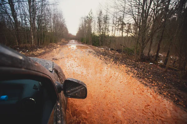 Suv 4wd voiture roule à travers la flaque d'eau boueuse, route de piste hors route, avec une grande éclaboussure, au cours d'une compétition jeeping — Photo