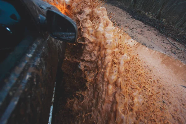 Geländewagen fährt durch schlammige Pfützen, Off-Road-Strecke, mit einem großen Spritzer, während eines Jeep-Wettbewerbs — Stockfoto