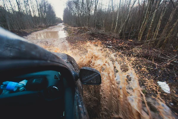 Suv 4wd voiture roule à travers la flaque d'eau boueuse, route de piste hors route, avec une grande éclaboussure, au cours d'une compétition jeeping — Photo