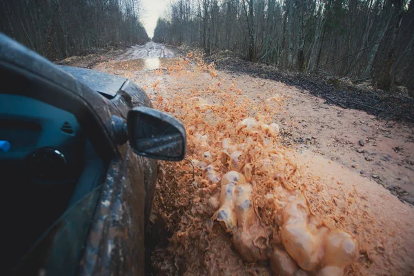 Suv 4wd gite in auto attraverso pozzanghera fangosa, strada fuoristrada, con un grande schizzo, durante una gara di jeep — Foto Stock