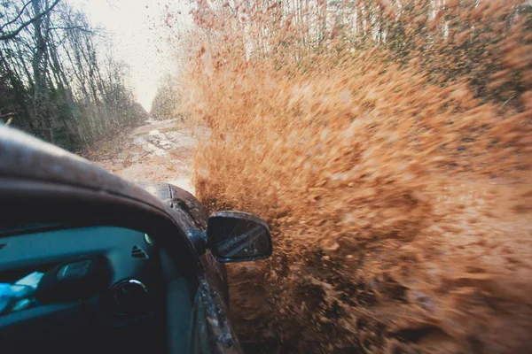 Suv 4wd coche paseos a través de charco fangoso, camino de la pista fuera de la carretera, con un gran chapoteo, durante una competencia jeeping —  Fotos de Stock