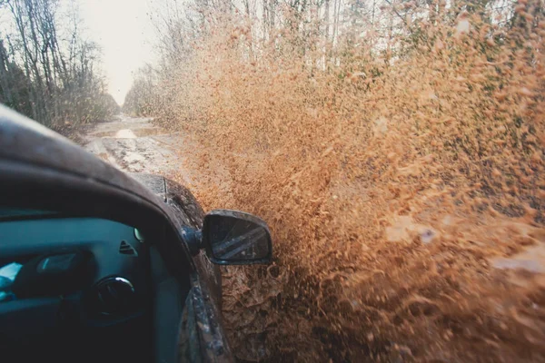 Suv 4wd gite in auto attraverso pozzanghera fangosa, strada fuoristrada, con un grande schizzo, durante una gara di jeep — Foto Stock