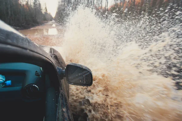 Suv 4wd voiture roule à travers la flaque d'eau boueuse, route de piste hors route, avec une grande éclaboussure, au cours d'une compétition jeeping — Photo