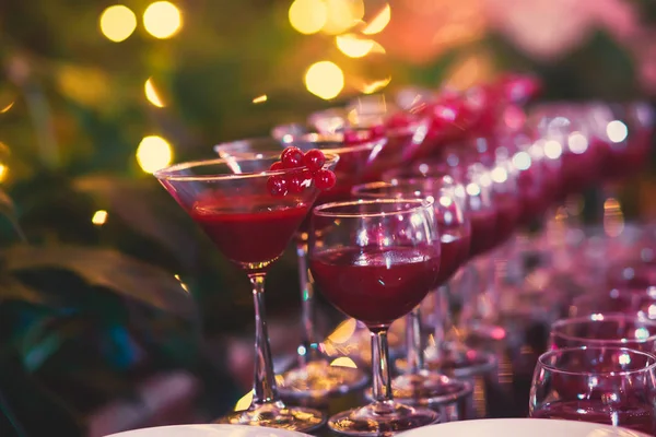 Hermosa línea de cócteles de diferentes colores en una fiesta al aire libre, tequila, martini, vodka y otros en la mesa de ramo de catering decorado en la fiesta al aire libre —  Fotos de Stock