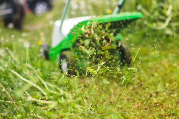 Un processus de tonte de pelouse, concept de tonte de la pelouse, tondeuse à gazon couper l'herbe avec des outils de jardinage et de l'herbe verte autour — Photo