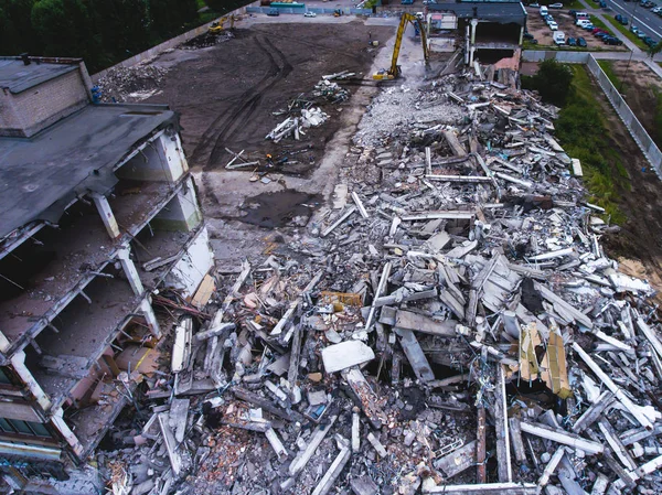 A process of buliding demolition, demolition site with heavy bulldozer and excavator with crushing equipment at work, demolished house, shot from air with drone — Stock Photo, Image