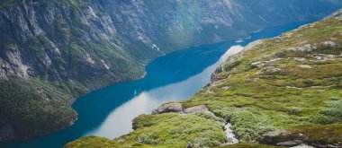 Canlı resim ünlü Norveçli yürüyüş yer - yol trolltunga, troller dil, bir turist ile kaya skjegedall ve göl ringedalsvatnet ve dağ panoramik manzara epik görünümü, Norveç
