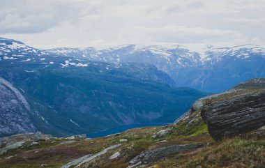 Canlı resim ünlü Norveçli yürüyüş yer - yol trolltunga, troller dil, bir turist ile kaya skjegedall ve göl ringedalsvatnet ve dağ panoramik manzara epik görünümü, Norveç