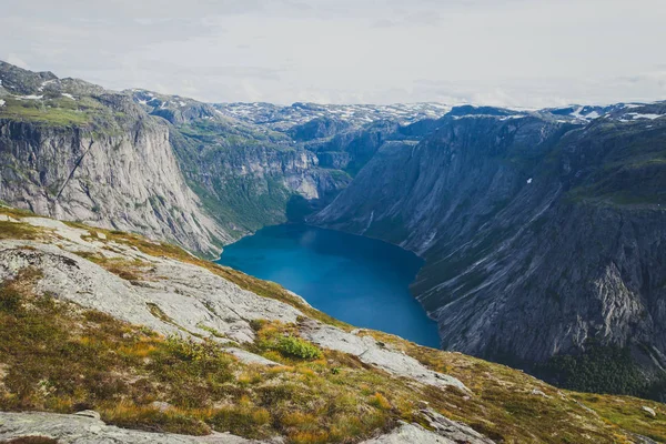 Ein lebhaftes Bild des berühmten norwegischen Wandergebietes - Weg nach Trolltunga, die Trollzunge, Rock skjegedall, mit einem Touristen, und See ringedalsvatnet und Bergpanorama epische Aussicht, Norwegen — Stockfoto