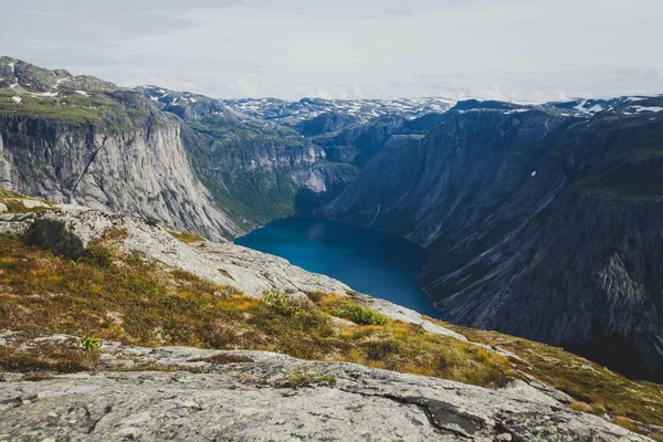 A vibrant picture of famous norwegian hiking place - way to trolltunga, the trolls tongue, rock skjegedall, with a tourist, and lake ringedalsvatnet and mountain panoramic scenery epic view, Norway — Stock Photo, Image