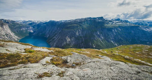 Ein lebhaftes Bild des berühmten norwegischen Wandergebietes - Weg nach Trolltunga, die Trollzunge, Rock skjegedall, mit einem Touristen, und See ringedalsvatnet und Bergpanorama epische Aussicht, Norwegen — Stockfoto