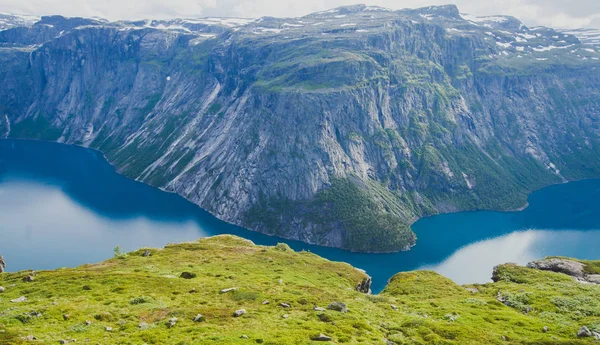 A vibrant picture of famous norwegian hiking place - way to trolltunga, the trolls tongue, rock skjegedall, with a tourist, and lake ringedalsvatnet and mountain panoramic scenery epic view, Norway — Stock Photo, Image