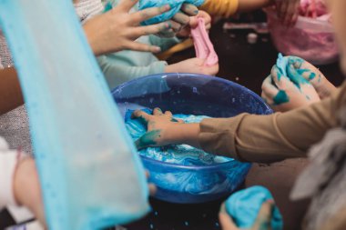 Çocukların doğum günü partisinde çok renkli balçık, pembe, mavi ve beyaz sümük oyuncağı yapan bir grup çocuk, sümükle oynayan çocuk, ev yapımı balçık.