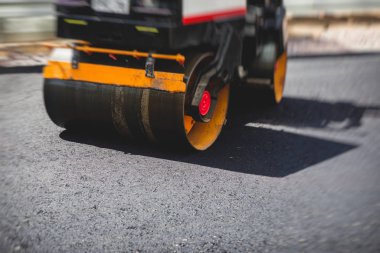 Yol yapımı sırasında asfalt kaldırım makinesi ve buharlı yol silindiri ve tamirat işleri, asfaltlama ve asfalt döşeme süreci, yeni yol inşaatında çalışan işçiler, bir katman yerleştirme