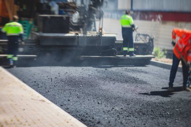 Yol yapımı sırasında asfalt kaldırım makinesi ve buharlı yol silindiri ve tamirat işleri, asfaltlama ve asfalt döşeme süreci, yeni yol inşaatında çalışan işçiler, bir katman yerleştirme