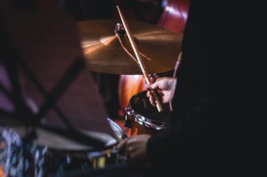 Jazz rock gösterisi sırasında sahnede davul setinin görüntüsü, arka planda orkestra performansı, davulcu poin