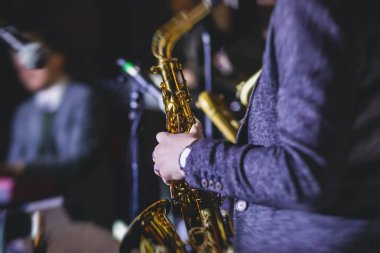 Caz grubu sırasında vokalist ve müzikal olan profesyonel saksafoncu bir kadının konser görüntüsü.