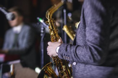 Caz grubu sırasında vokalist ve müzikal olan profesyonel saksafoncu bir kadının konser görüntüsü.