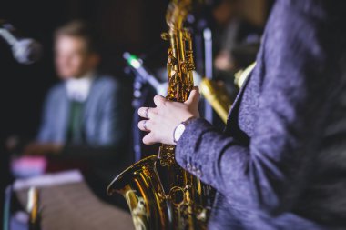 Caz grubu sırasında vokalist ve müzikal olan profesyonel saksafoncu bir kadının konser görüntüsü.