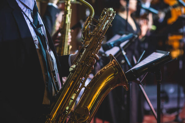Концертный взгляд саксофониста, саксофониста с вокалистом и мюзиклом во время исполнения джазового оркестра музыки на мальчишнике
