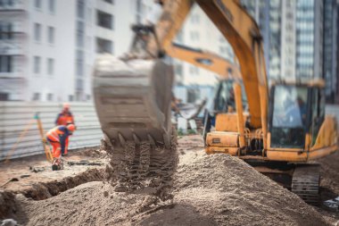 Sarı ağır kazıcı kumu kazıyor ve yol çalışmaları sırasında çalışıyor, yeni yol inşaatı sırasında kumu boşaltıyor