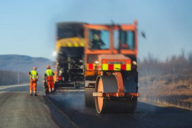 Yol yapımı sırasında asfalt kaldırım makinesi ve buharlı yol silindiri ve tamirat işleri, asfaltlama ve asfalt döşeme süreci, yeni yol inşaatında çalışan işçiler, bir laye yerleştirme