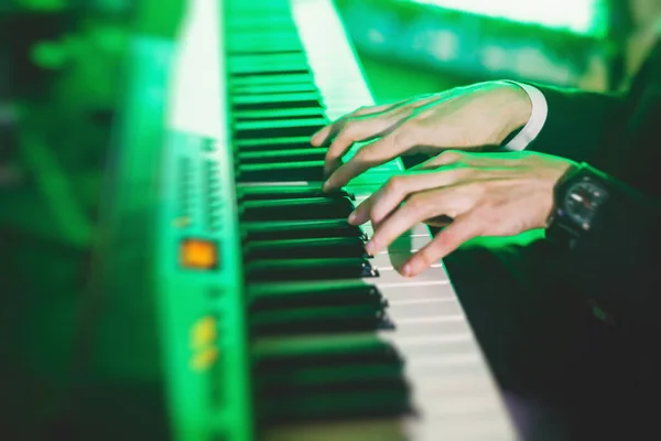 Concert view of a musical keyboard piano player during musical jazz band performing in the backgroun