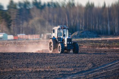 Disk harrow sistemine sahip bir traktör ekili tarım tarlasını, toprağı yıpratma ve hazırlama sürecini, gün batımında tarlada ekin ekme işini, tarım kavramını, Wor 'da harrow makinesini,