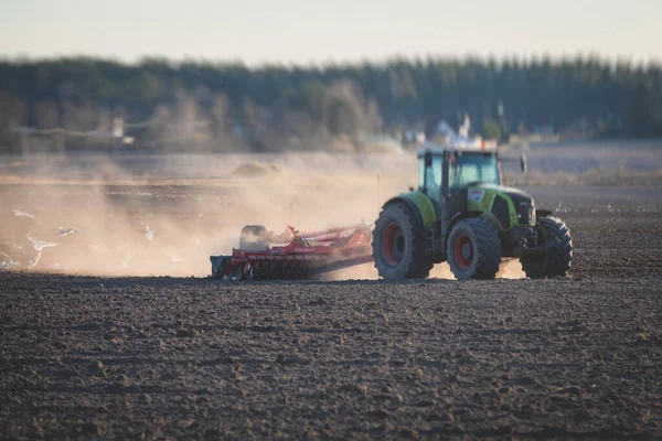 ディスクの収穫システムを持つトラクターは 耕作された農場を耕し 土壌を耕し 準備するプロセス 日没時に畑で作物を播種するトラクター 農業コンセプト 機械を耕します — ストック写真